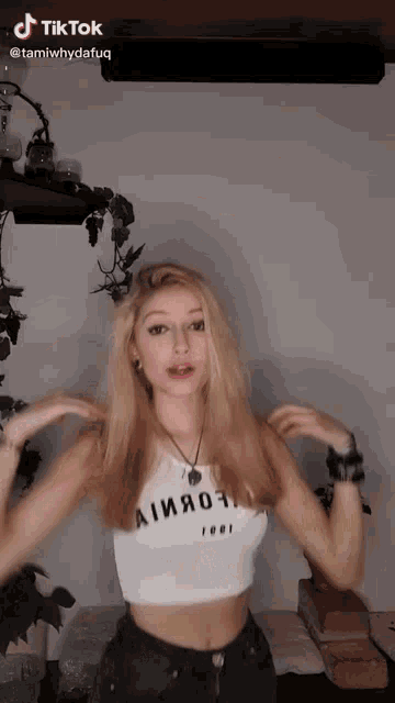 a woman is wearing a white crop top that says almost