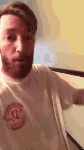 a man with a beard is wearing a white t-shirt with a red circle on the front .