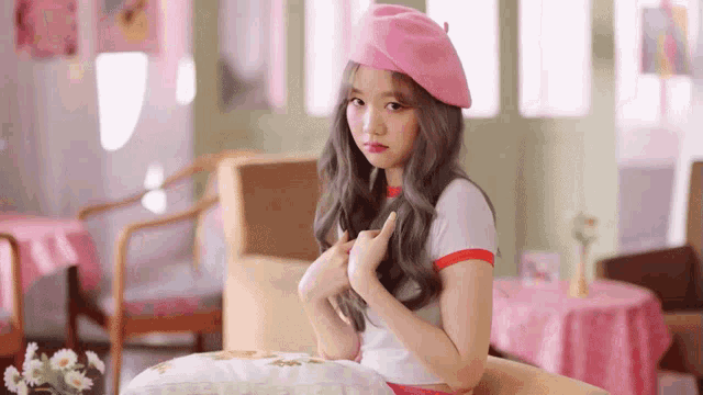 a girl wearing a pink beret is sitting on a chair