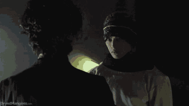 a man and a woman are looking at each other with the website dryedmangoez.com visible in the corner