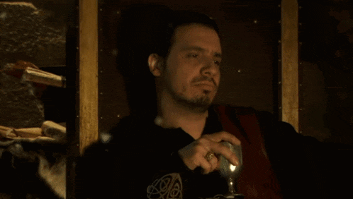 a man with a beard and a ring on his finger holds a glass