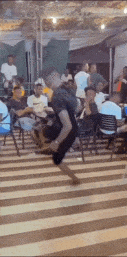 a man is dancing on a striped floor in front of a crowd of people .