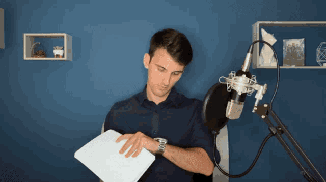 a man in a blue shirt stands in front of a microphone