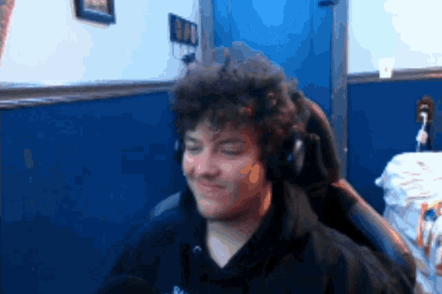 a man with curly hair wearing headphones and a black shirt that says ' bad '