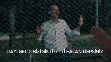 a man standing behind a chain link fence with the words dayi geldi bizi sikti gitti falan dersiniz