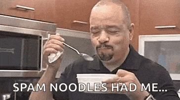 a man is eating noodles with a spoon and saying `` spam noodles had me '' .