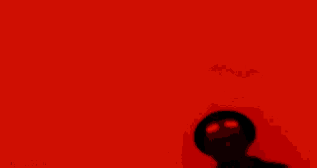 a silhouette of a man in a top hat with red eyes in front of a red background .