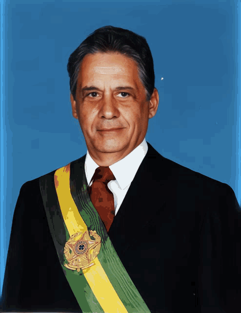 a man in a suit and tie with a yellow and green sash around his neck