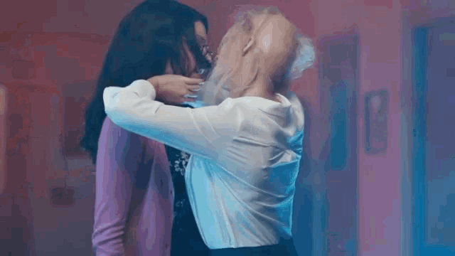 two women are hugging each other in a dark room .