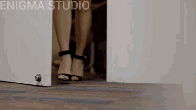 a woman in high heels is walking through an open door with enigma studio written on the bottom