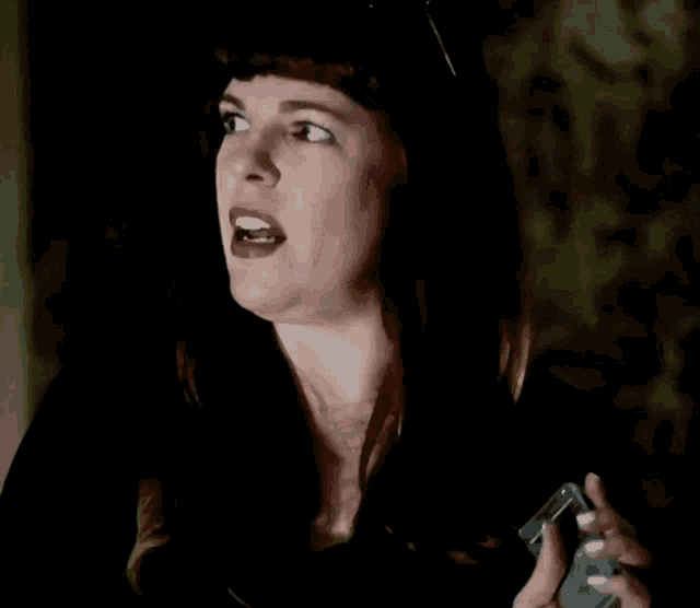 a woman in a black hat is holding a cell phone in her hand