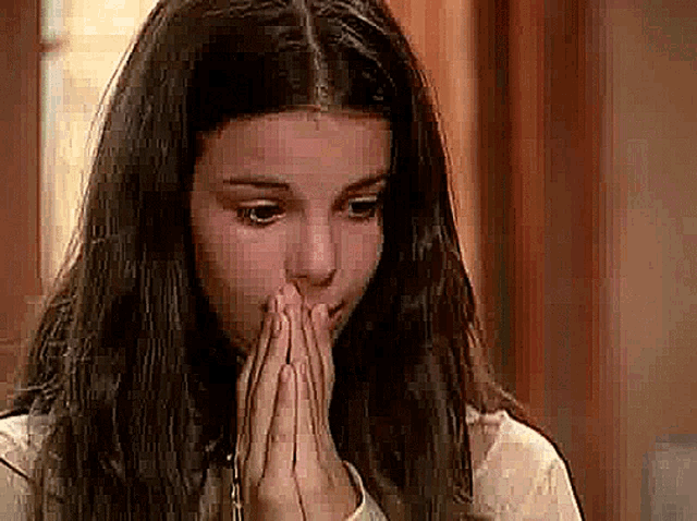 a young girl with long hair is praying with her hands folded .