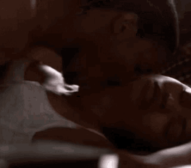 a man is kissing a woman on the neck while they are laying on a bed .