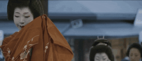 a woman in a red kimono is dancing in a room