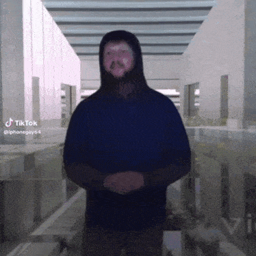 a man in a hoodie is standing in a hallway with tiktok written on the bottom right corner