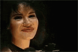 a woman with a big smile on her face is making a funny face and waving her hand .