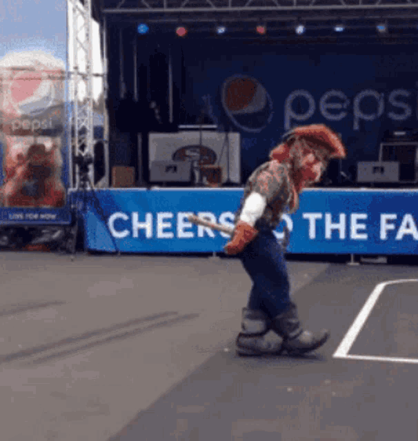 a man in a cowboy costume is dancing in front of a pepsi sign