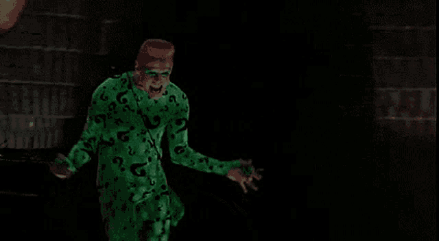 a man in a green costume with a red hat is standing in the dark