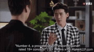 a man in a plaid suit and tie is talking to another man in a suit .