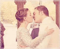 a man and woman are kissing in front of a crowd of people .