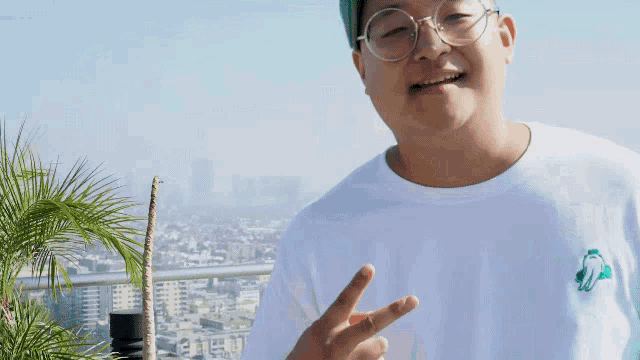 a young man wearing glasses and a white shirt is giving a peace sign