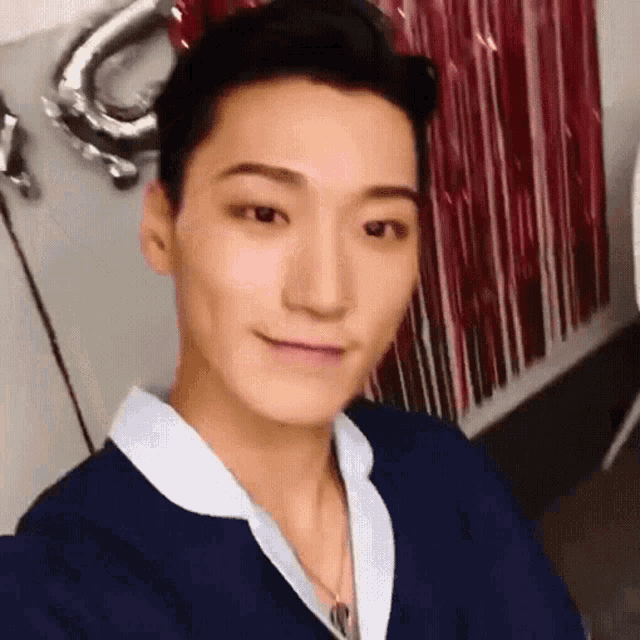 a young man in a blue shirt is taking a selfie .