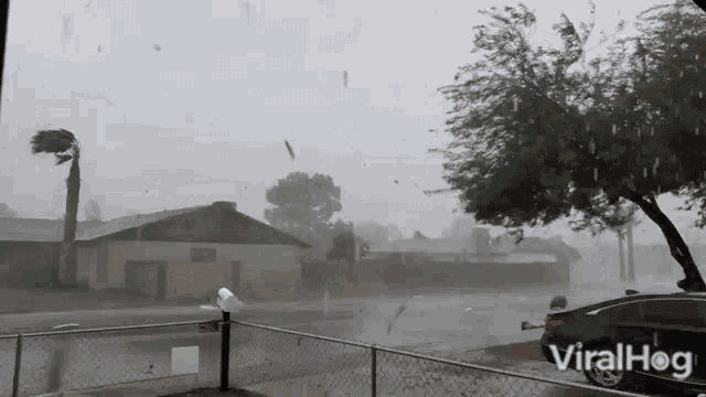 a car is parked in front of a fence during a storm with the words viralhog on the bottom