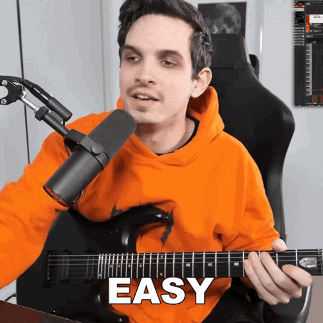 a man in an orange hoodie is playing a guitar and the word easy is on the bottom