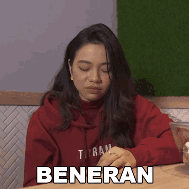 a woman wearing a red hoodie that says tyran beneran