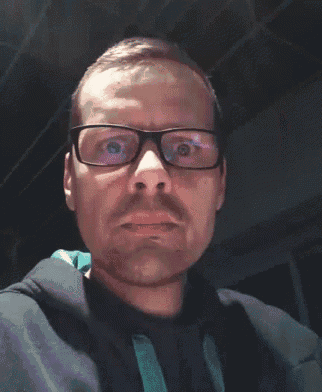 a man wearing glasses and a black jacket is making a face
