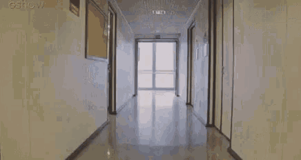 two women are dancing in a hallway while another woman looks on .