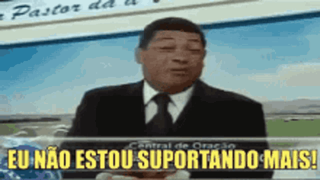 a man in a suit and tie is standing in front of a sign that says eu nao estou suportando mais