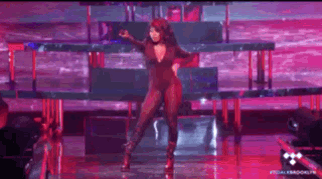 a woman is dancing on a stage wearing a red bodysuit .