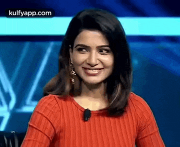 the woman is wearing a red sweater and smiling .
