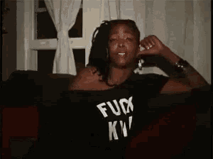 a woman with dreadlocks is wearing a black shirt that says fuck kw