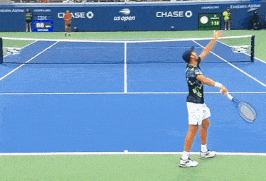 a tennis player reaches up to catch a tennis ball in front of a chase banner