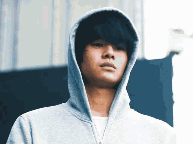 a man wearing a grey hoodie with a white shirt underneath it