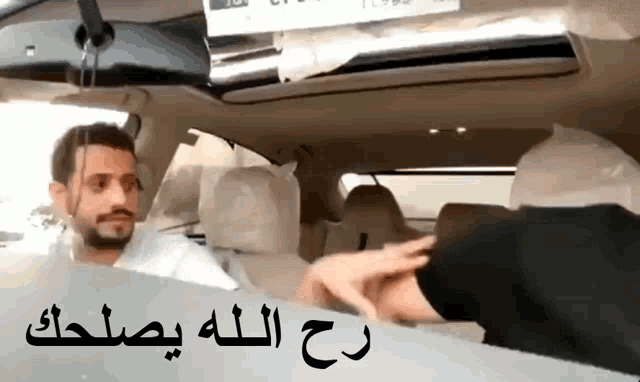 a man is sitting in a car with arabic writing on the side