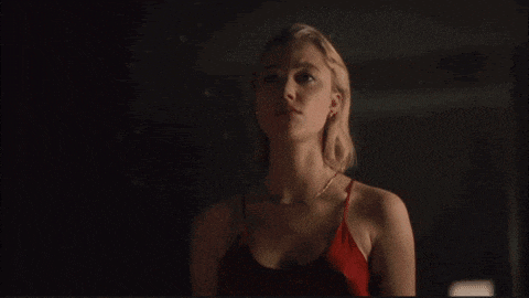 a woman in a red tank top is looking at something