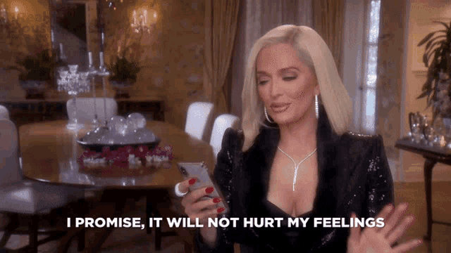 a woman is holding a cell phone and says " i promise it will not hurt my feelings "