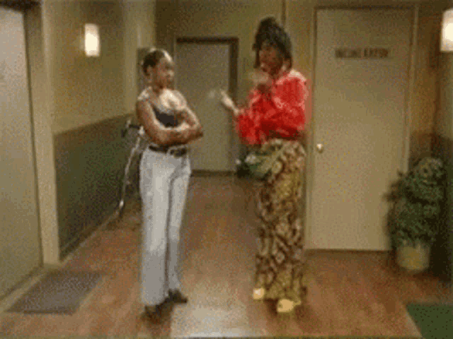 a man in a red shirt is dancing in a hallway next to a woman