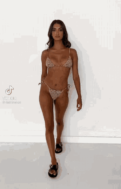 a woman in a bikini is walking on a white surface .