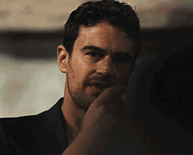 a close up of a man 's face with his hand to his chin