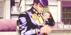 a man in a purple suit is standing in front of a building looking at his watch
