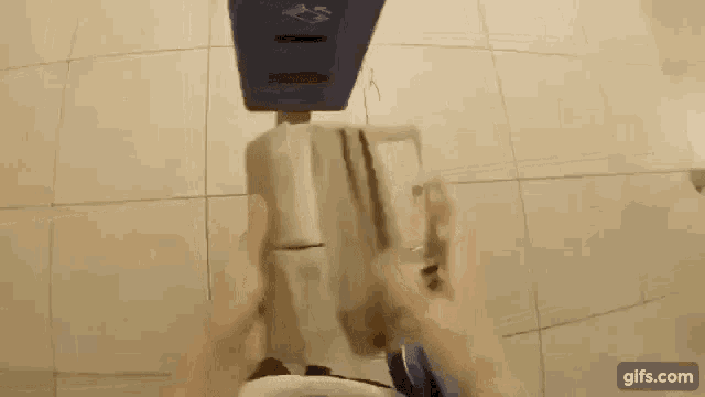 a person is sitting on a toilet holding a box that says tickets on it .