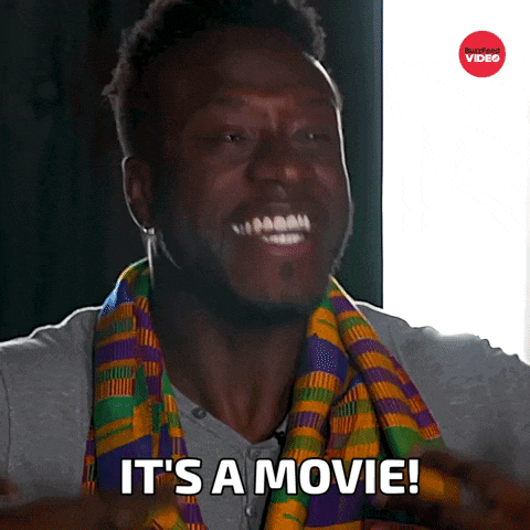 a man with a scarf around his neck is smiling and says it 's a movie
