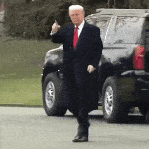 a man in a suit and red tie is giving a middle finger