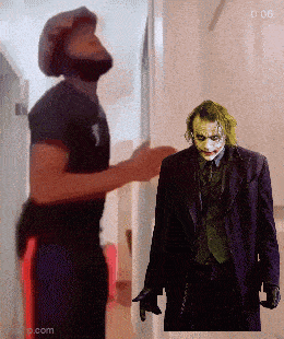 a man standing next to a picture of the joker with the time 0:06