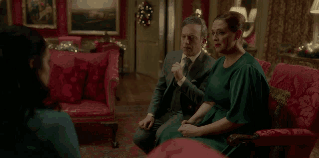 a woman in a green dress sits next to a man in a suit and tie