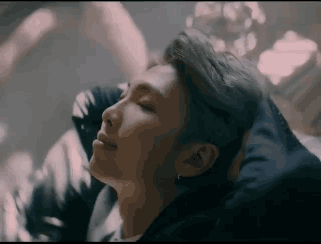 a close up of a man 's face with his eyes closed in a dark room